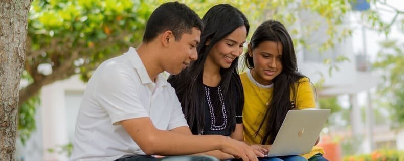 Tres estudiantes trabajando juntos frente a un computador.