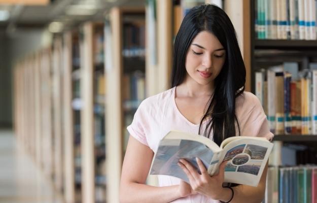 estudiante en la biblioteca leyendo un libro