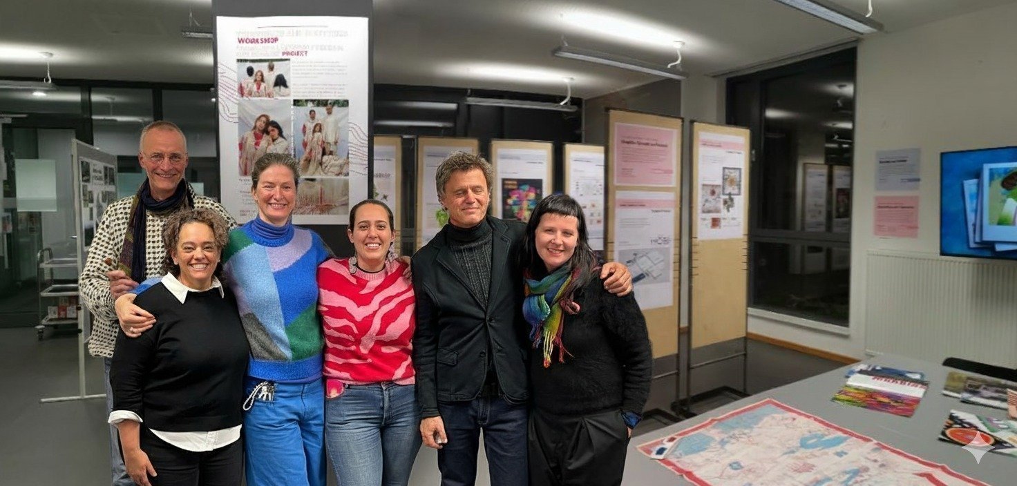 Grupo de seis personas posando y sonriendo en una sala de exposición, con carteles y un tablero con mapas al fondo.