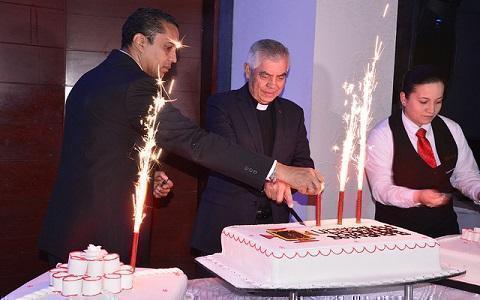 Rector junto a la torta con las velas encendidas durante el canto de cumpleaños a la UPB