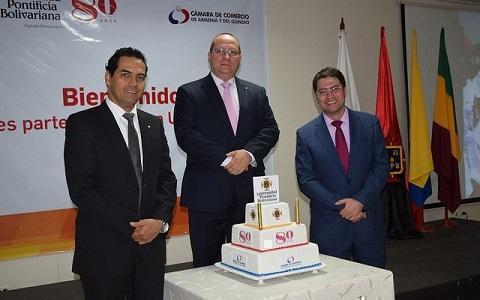 Directivos posando para una foto detrás de la torta de cumpleaños de la UPB