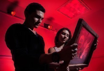 Dos estudiantes viendo un cuadro en habitación con luces rojas