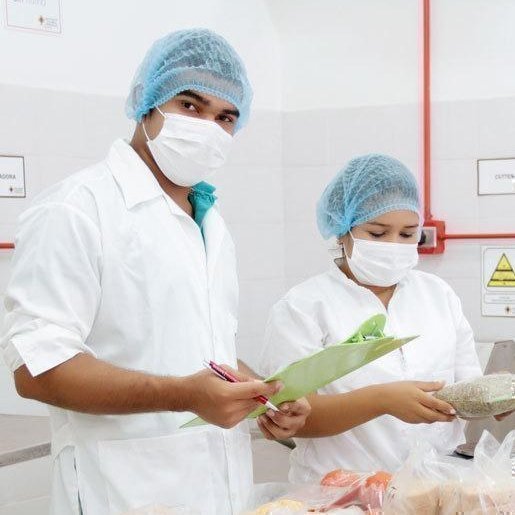 Ingenieros agroindustriales con tapabocas y delantales, trabajando en el tratamiento de alimentos.