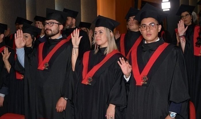 Estudiantes con toga de graduación en auditorio