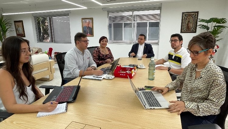 Personas reunidas alrededor de una mesa hablando y con computadores